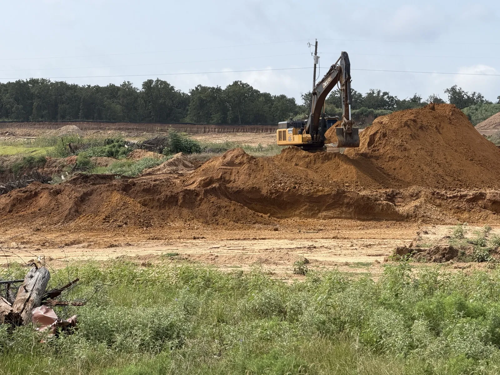 Texas Best Demolition excavator working a dirt stockpile near Burleson